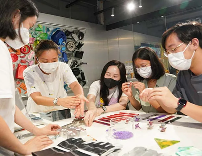 一组参与者在工作台旁用再生塑料制作物件