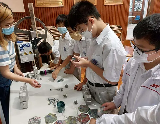 学生在塑料回收设备旁观察小物件